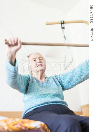 Elderly 96 years old woman exercising with a stick sitting on her bad. 55117490
