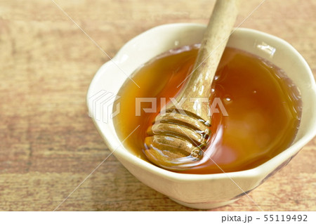 honey and wooden scoop in cup on table 55119492