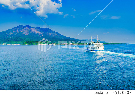 [鹿児島県の観光イメージ] 初夏の快晴の下，噴煙をあげる桜島に向かう桜島フェリーと海上の航跡 55120207