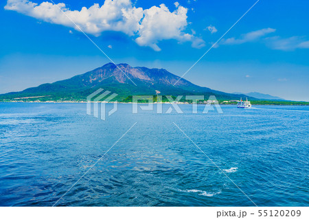 [鹿児島県の観光イメージ] 初夏の快晴の下，噴煙をあげる桜島に向かう桜島フェリーと海上の航跡 55120209