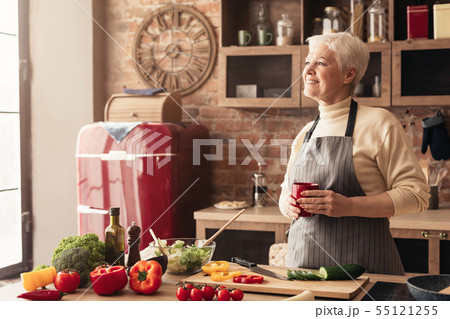 Pensive retired lady enjoying coffee break at kitchen Pensive retired lady enjoying coffee break at kitchen 55121255