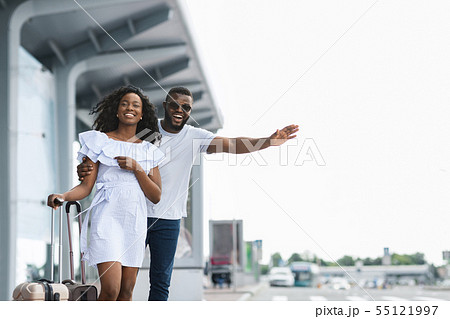 Young african couple standing near airport trying to stop car 55121997