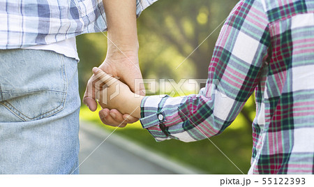 Father holds daughter by the hand while walking 55122393