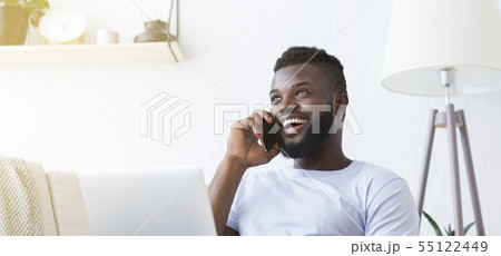 Millennial man talking by cellphone and using laptop Millennial man talking by cellphone and using laptop 55122449