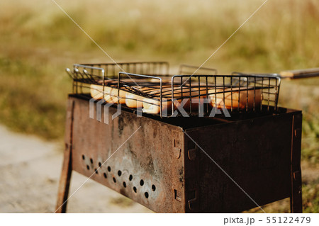 Delicious grilled sausages resting on the iron grid of a portable barbecue 55122479