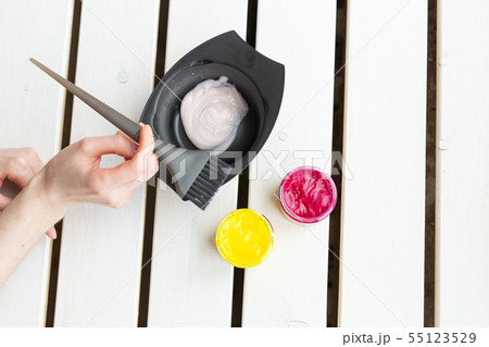 Color and hairdresser concept - female hairdresser in process of mixing hair dye color on the table Color and hairdresser concept - female hairdresser in process of mixing hair dye color on the table 55123529