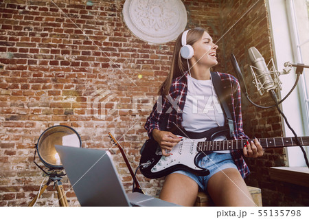 Woman recording music, playing guitar and singing at home 55135798
