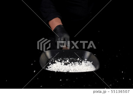 Chef in black uniform holds a pan with white salt 55136507