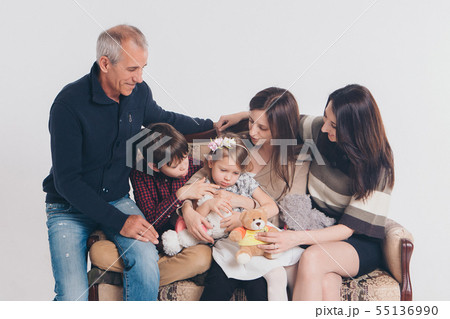 adults and children with toy sitting on same couch 55136990
