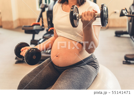 Active pregnant woman exercise in fitness center. Active pregnant woman exercise in fitness center. 55141471