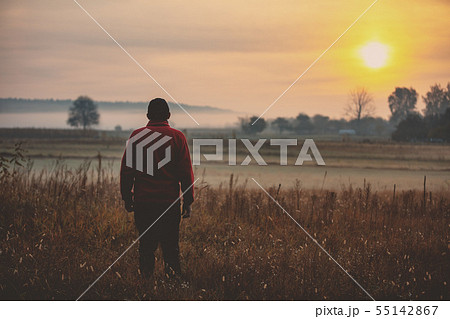 Man standing in the field early in the morning Man standing in the field early in the morning 55142867