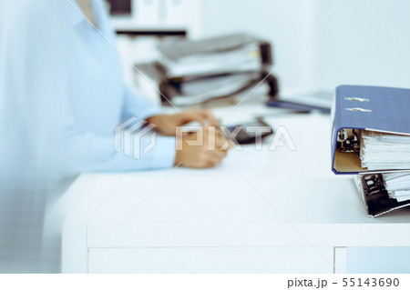 Binders with papers are waiting to be processed by business woman or bookkeeper back in blur 55143690
