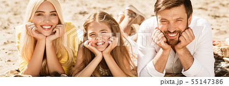 Happy family lying on blanket and smiling to camera Happy family lying on blanket and smiling to camera 55147386