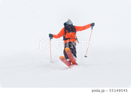 Professional Skier athlete rides out of deep snow while performing a skiing trick in a snowstorm 55149545