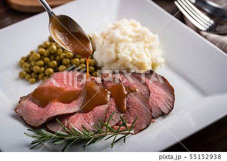 pouring gravy sauce on sliced roasted beef with pouring gravy sauce on sliced roasted beef with 55152938
