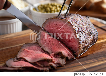 slicing eye of round roasted beef with knife 55152941