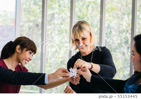 Diverse business people putting puzzle pieces together Diverse business people putting puzzle pieces together 55153445