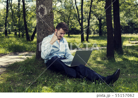 Young man working on his laptop in a public park Young man working on his laptop in a public park 55157062