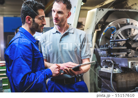 Two workers discussing a project in front of CNC lathe machine Two workers discussing a project in front of CNC lathe machine 55157610