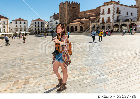 A young red-haired tourist with a backpack makes a selfie in the Plaza Mayor de Caceres A young red-haired tourist with a backpack makes a selfie in the Plaza Mayor de Caceres 55157739