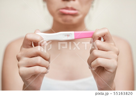 Unhappy young asian woman holding pregnancy test 55163820