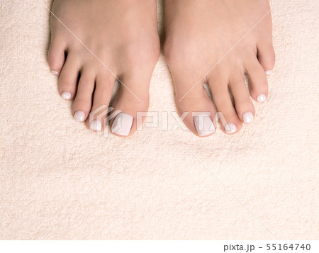 Female bare feet, toes with white pedicure on ivory terry towel, close up. Female bare feet, toes with white pedicure on ivory terry towel, close up. 55164740