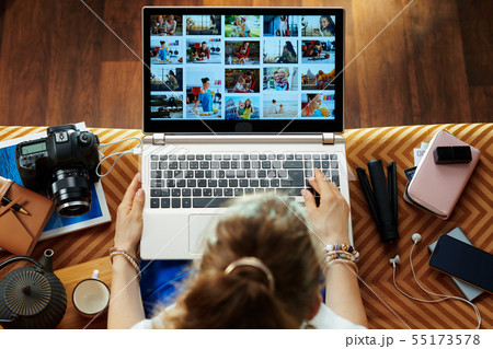 woman looks at image while transferring photos from DSLR camera 55173578