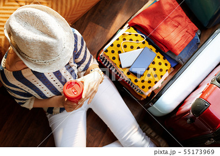 young woman with coffee cup near open travel suitcase 55173969