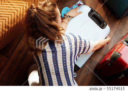 stylish woman closing over packed suitcase 55174015