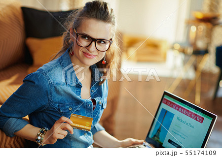 woman with online travel site on laptop holding gold credit card 55174109