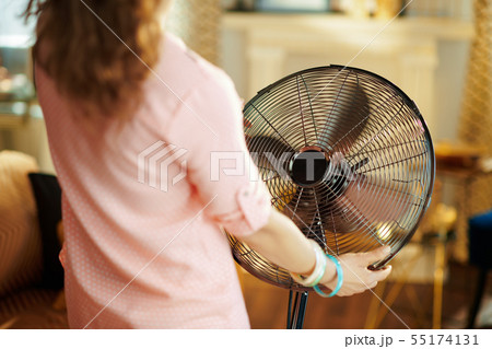 stylish housewife cooling down in front of fan stylish housewife cooling down in front of fan 55174131
