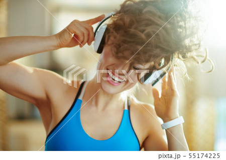 woman listening to music with headphones in modern house 55174225
