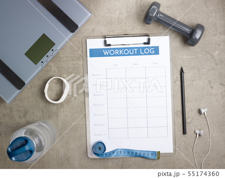 weight scales, black pen and workout log on clipboard 55174360