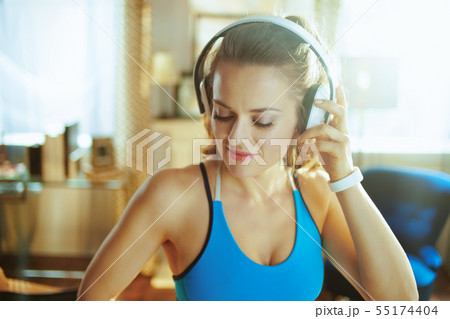 young woman listening to music with headphones in modern house young woman listening to music with headphones in modern house 55174404