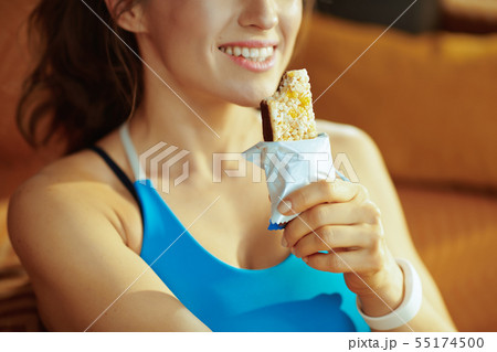 Closeup on smiling young sports woman eating fitness bar Closeup on smiling young sports woman eating fitness bar 55174500