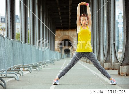 sports woman on Pont de Bir-Hakeim bridge in Paris stretching 55174703