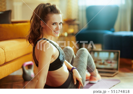 sports woman and watching fit tutorial on internet via laptop 55174818