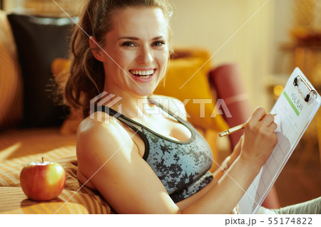 smiling woman with apple and clipboard filling meal plan 55174822