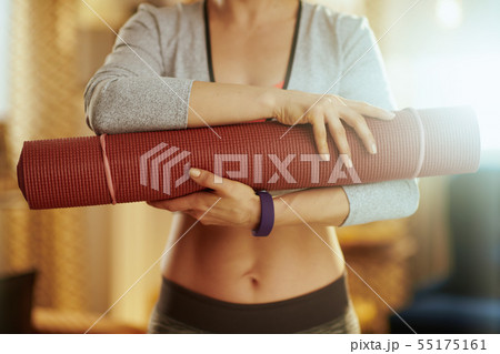 Closeup on fitness mat in hands of fit woman at modern home Closeup on fitness mat in hands of fit woman at modern home 55175161