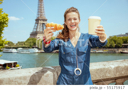 happy young woman showing cup of coffee and croissant happy young woman showing cup of coffee and croissant 55175917