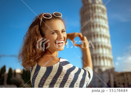 woman against leaning tower showing heart shaped hands woman against leaning tower showing heart shaped hands 55176684