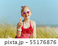 modern girl in red swimwear holding lipstick with spf on beach 55176876