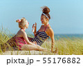 smiling mother and child on ocean coast applying sun screen 55176882