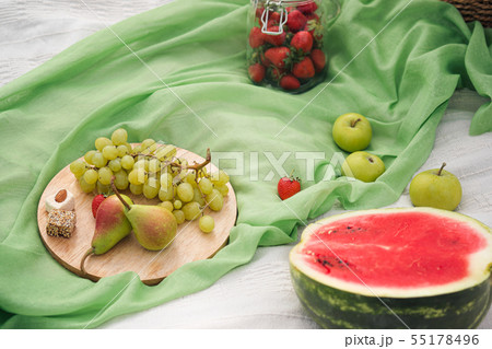 Summer picnic in the meadow on the green grass. Fruit basket, juice and bottled wine, watermelon 55178496