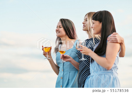 Three young attractive women, in blue dresses are walking along the seashore. Girlfriends Three young attractive women, in blue dresses are walking along the seashore. Girlfriends 55178536
