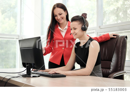 Two young women work in a bright office at the computer. Discuss workflows and enjoy a successful Two young women work in a bright office at the computer. Discuss workflows and enjoy a successful 55183003