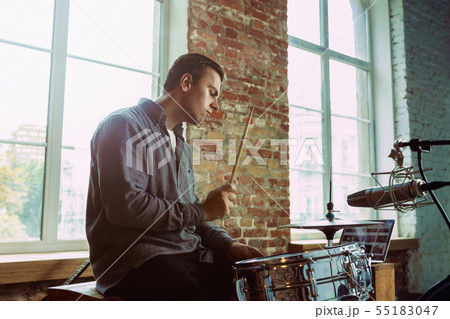 Young man recording music, playing drums and singing at home 55183047