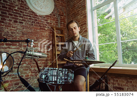 Young man recording music, playing drums and singing at home Young man recording music, playing drums and singing at home 55183074