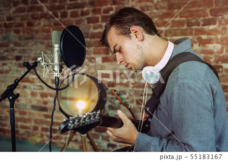 Young man recording music, playing guitar and singing at home Young man recording music, playing guitar and singing at home 55183167