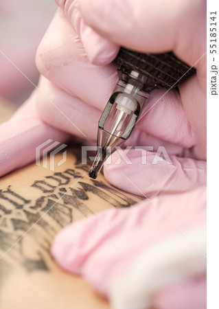 Close-up of a tattoo needle. The process of the tattoo master. Pink women's protective gloves. Close-up of a tattoo needle. The process of the tattoo master. Pink women's protective gloves. 55185141